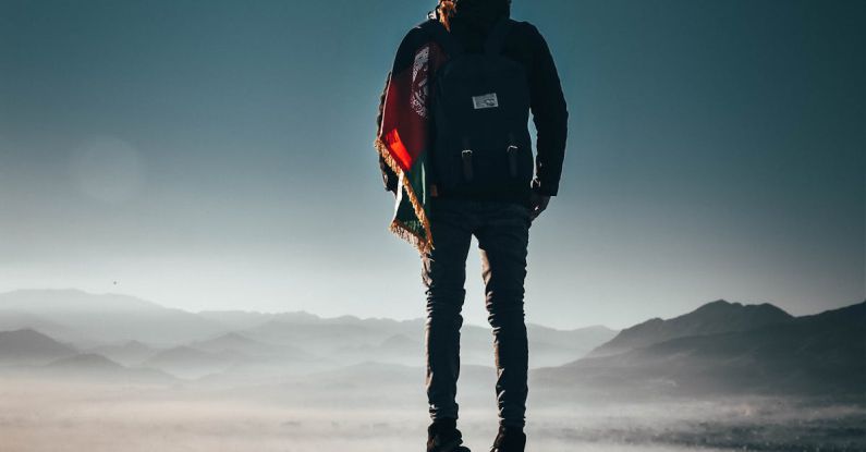 Adventure - Man Carrying Backpack Standing on Rock Formation