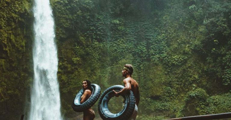 Adventure - Two Person Carrying Black Inflatable Pool Float on Brown Wooden Bridge Near Waterfalls