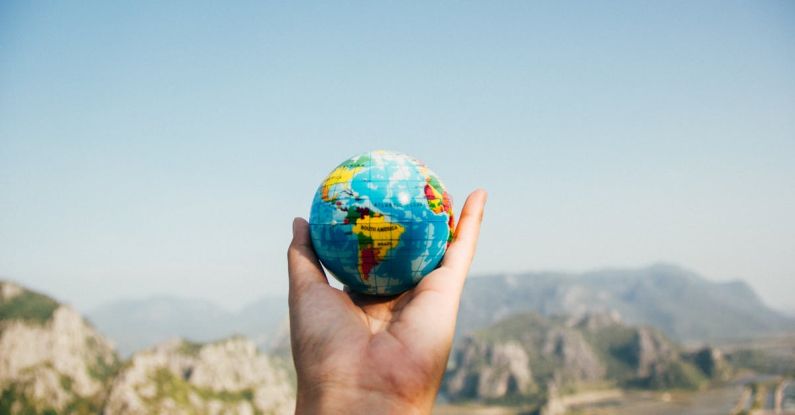 Adventure - Person Holding World Globe Facing Mountain