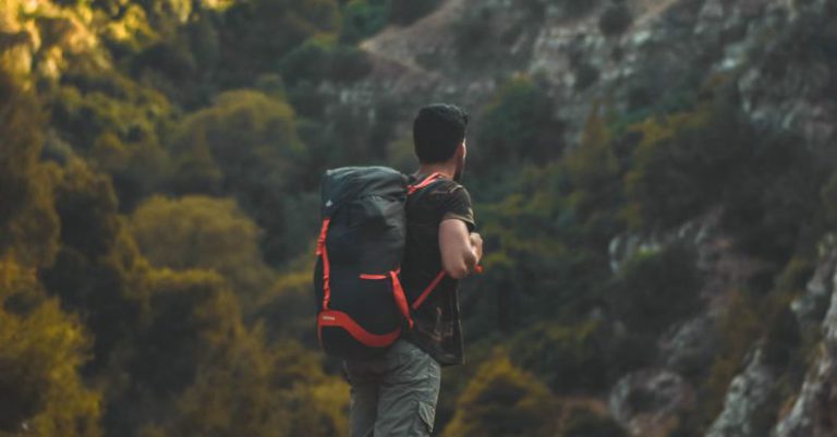 Hiking - Man in Black T-shirt Carrying a Bag-pack Standing on Cliff